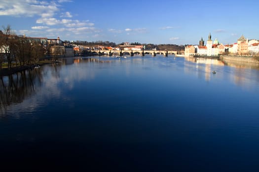 Photo shows various historical houses, Vltava river, bridges and other architectural details.