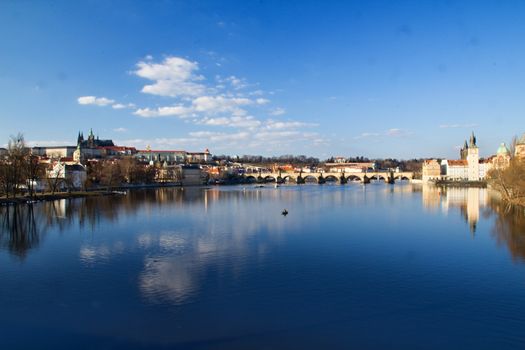 Photo shows various historical houses, Vltava river, bridges and other architectural details.