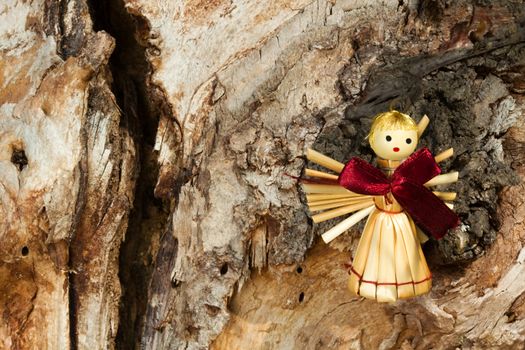 Photo shows a straw angel figurine in the wood.