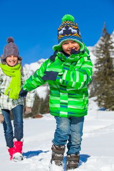 Two happy kids playing winter on the snow in Alps