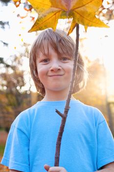 Portrait of a Boy Holding a Brown Leaf Outdoors