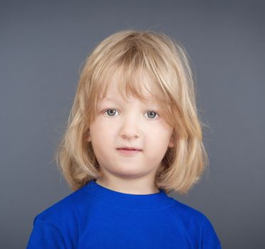 studio portrait of a boy with long blond hair - isolated on gray