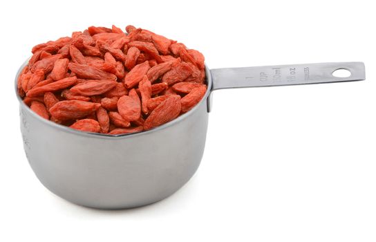 Red goji berries in an American cup measure, isolated on a white background