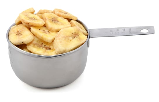 Dried banana chips in an American cup measure, isolated on a white background