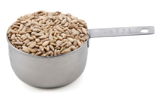 Hulled sunflower seeds in an American cup measure, isolated on a white background