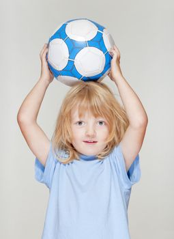 boy with long blond hair holding a football - isolated on light gray