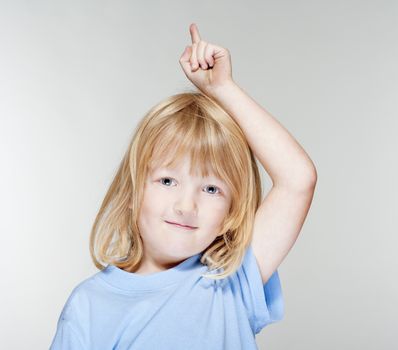 boy with long blond hair pointing up - isolated on gray