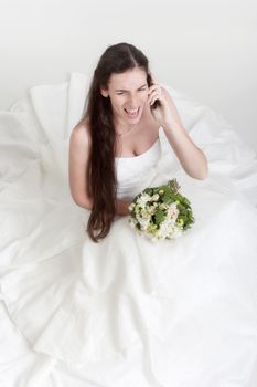 angry bride in wedding dress and bouquet yelling in mobile phone