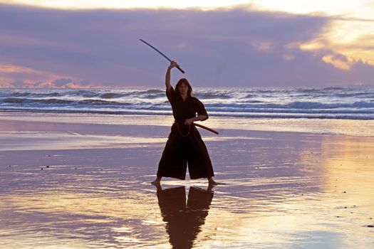 Young samurai women with Japanese sword(Katana) at sunset on the beach