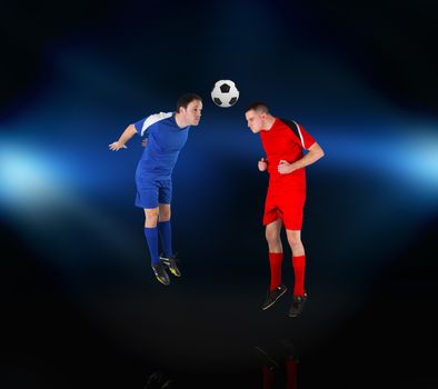 Football players tackling for the ball on black background with lights