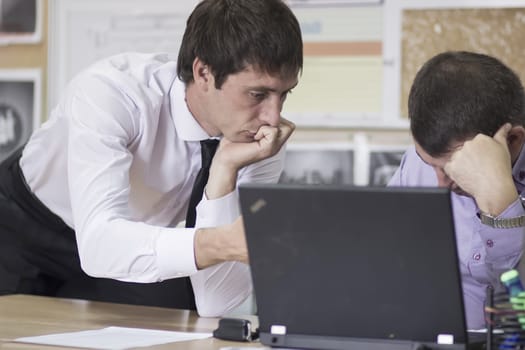 Two managers in the office to discuss his laptop