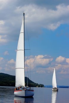 Two sailboats on peaceful still waters in a harbor.