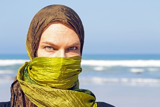 Beautiful arabic woman with green scarf at the ocean