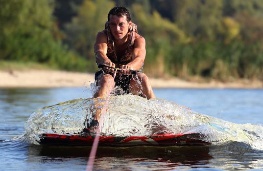 Wet athlete driving a wave on the wakeboard