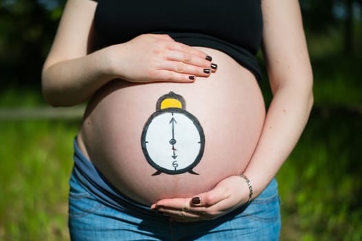 Pregnant woman with clock painted on her belly