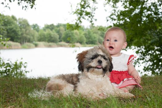 Baby and puppy are playing near the lake