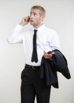 portrait of a young businessman talking on cell phone - isolated on gray