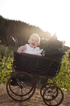 Baby girl is sitting in a vintage pram