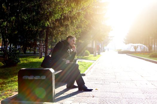 Toned photo of Cheerful Young Man with Mobile Phone at the Autumn Park