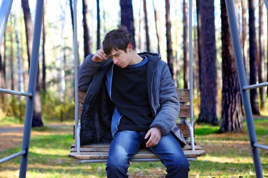 Lonely Sad Teenager sitting in the Autumn park