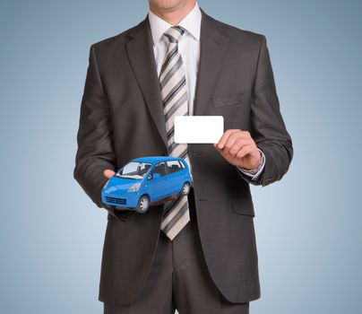 Businessman in suit hold empty card and small car. Blue background