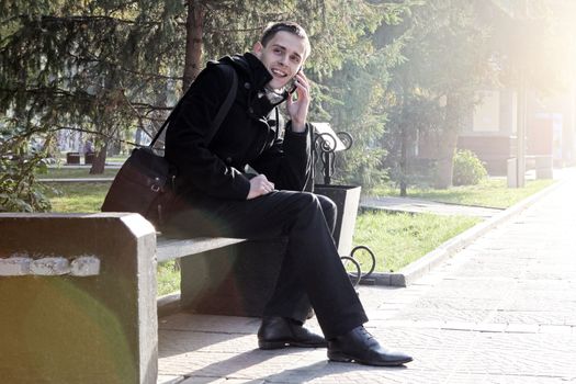 Toned photo of Cheerful Young Man with Mobile Phone at the Autumn Park