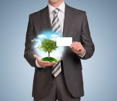 Businessman in suit hold empty card and nature landscape with tree. Blue background