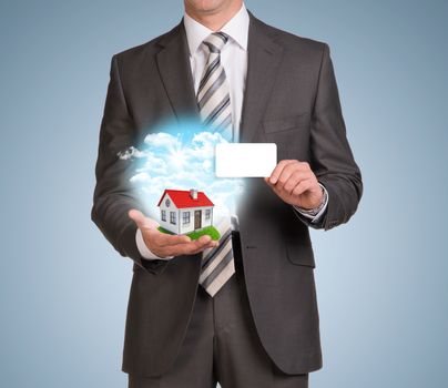 Businessman in suit hold empty card and nature landscape with small house. Blue background