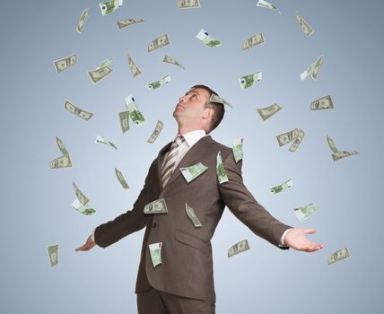 Businessman in suit spread his arms and looking up. Money fall from above