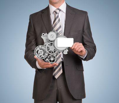 Businessman in suit hold empty card and clockwork. Blue background