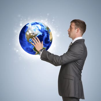 Businessman in suit hold Earth. Elements of this image are furnished by NASA