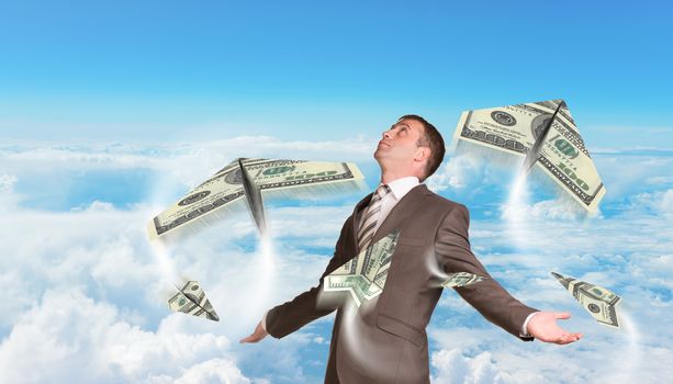 Businessman in suit spread his arms and looking up. Paper airplanes made of hundred dollar bills