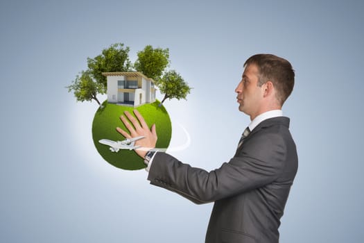 Businessman hold Earth with small house and trees. Blue background