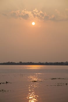 sun is falling In front of a lake The water of the lake reflecting the sun.