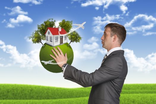 Businessman hold Earth with small house and trees. Nature landscape as backdrop