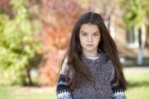 Close up portrait of a beautiful nine year old little girl in autumn park