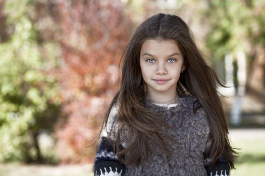 Close up portrait of a beautiful nine year old little girl in autumn park