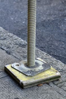 Close up on one scaffold foot upon a piece of wood in the street