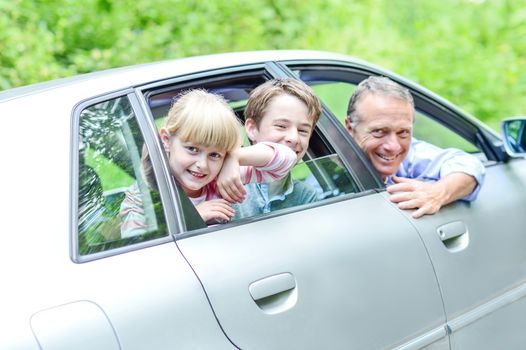 Father with his kids posing from car looking out windows