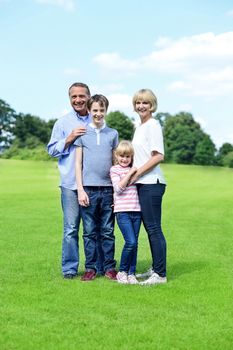 Happy family of four standing together on the meadow