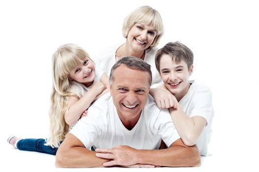 Family of four lying on top of each other  and posing to camera