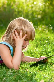 Little girl usng a touch pad in a summer garden