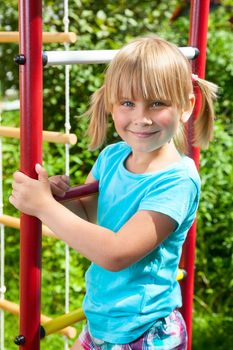 Portrait of cute little girl standing at monkey bars