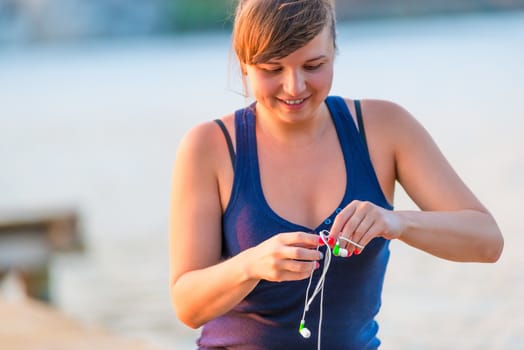 Active young woman unravels the earphones