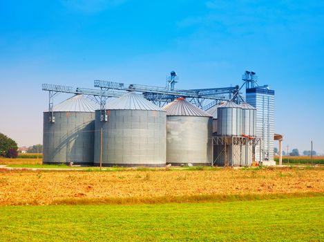 Industrial silos under blue sky, in the fields