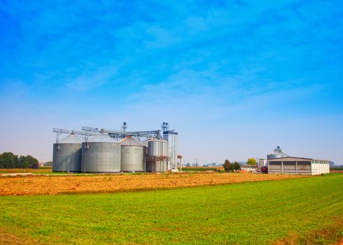 Industrial silos under blue sky, in the fields