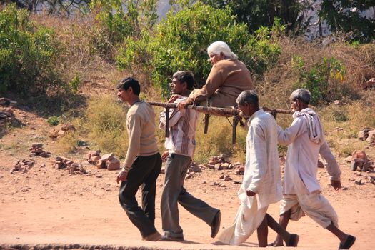Local men carrying old woman at Ranthambore Fort, Rajasthan, India