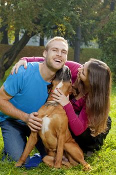 Happy Young Couple Playing with their Dog in the Park.