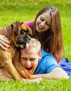 Happy Young Couple Playing with their Dog in the Park.