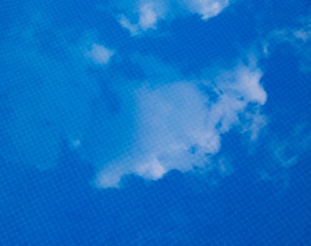 the reflection of white summer clouds, on the surface of a swimming pool